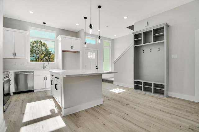 kitchen with pendant lighting, a center island, backsplash, white cabinets, and stainless steel dishwasher