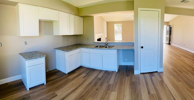 kitchen with stone counters, dark hardwood / wood-style flooring, white cabinetry, and sink