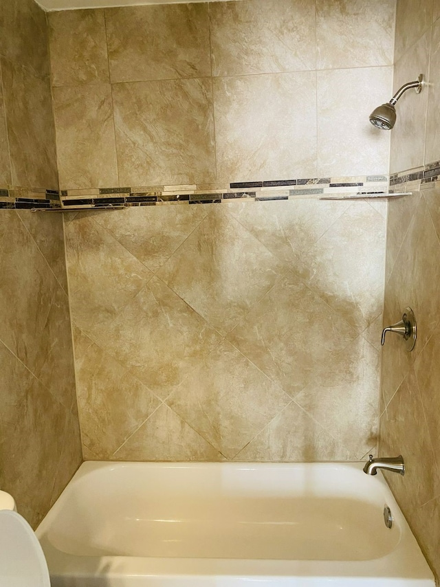 bathroom with tiled shower / bath and toilet