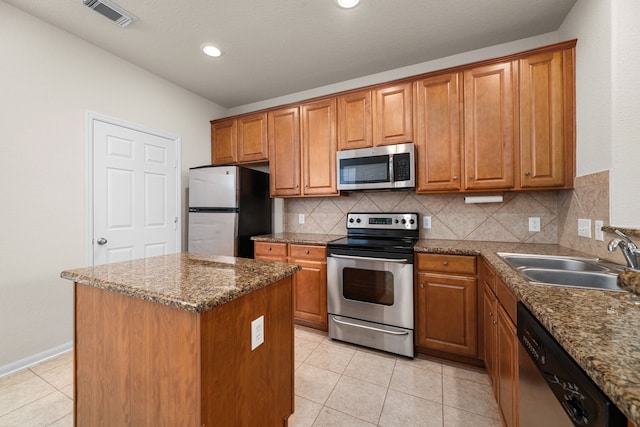 kitchen with tasteful backsplash, stainless steel appliances, sink, light tile patterned floors, and a kitchen island