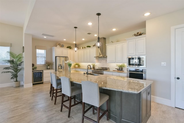 kitchen with stainless steel appliances, wine cooler, a large island, and wall chimney range hood