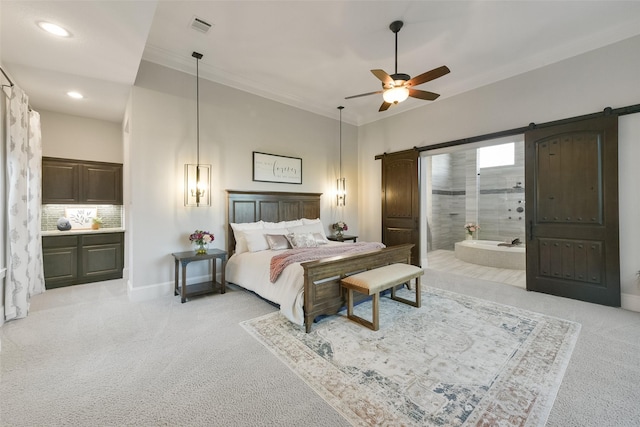 bedroom featuring a barn door, light carpet, ceiling fan, and ensuite bath