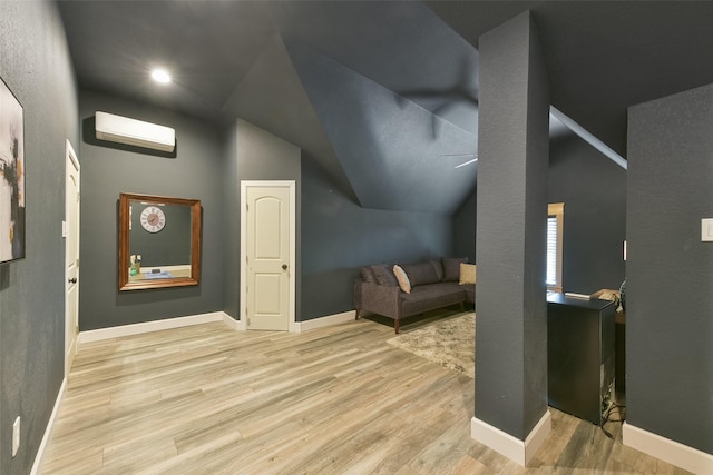 additional living space with light hardwood / wood-style floors, an AC wall unit, and vaulted ceiling