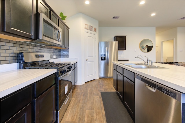 kitchen with sink, decorative backsplash, appliances with stainless steel finishes, butcher block countertops, and light hardwood / wood-style floors