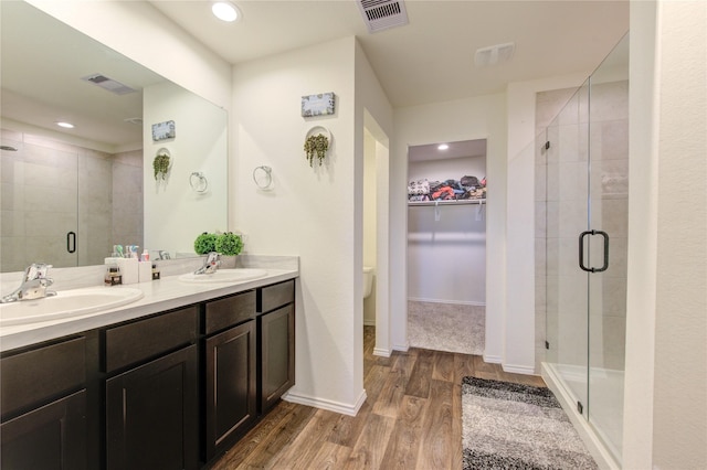 bathroom with toilet, vanity, a shower with shower door, and hardwood / wood-style flooring