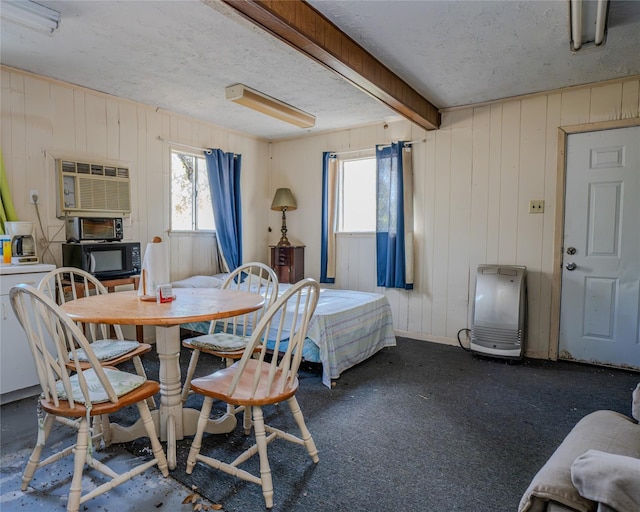 carpeted dining space with an AC wall unit, plenty of natural light, and wood walls