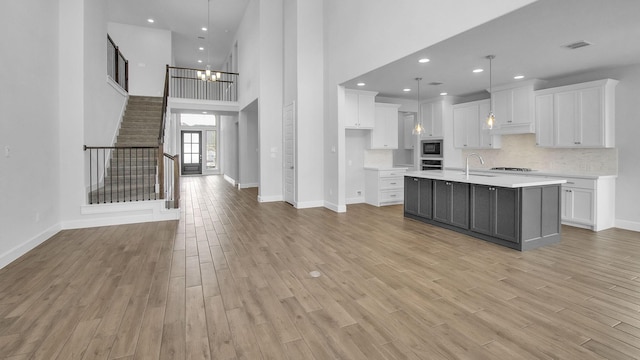 kitchen with a sink, white cabinetry, visible vents, light wood-type flooring, and built in microwave