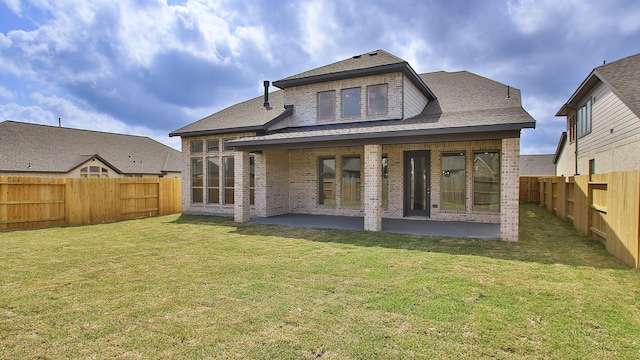 rear view of house featuring a fenced backyard, brick siding, roof with shingles, a lawn, and a patio area