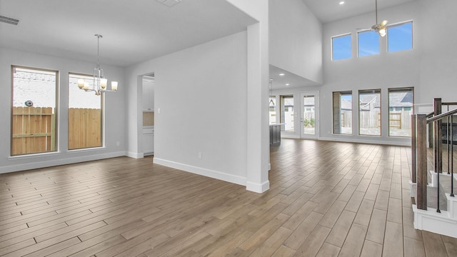 unfurnished living room with recessed lighting, baseboards, an inviting chandelier, and wood finished floors