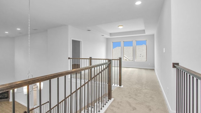 hall featuring carpet floors, recessed lighting, a raised ceiling, an upstairs landing, and baseboards