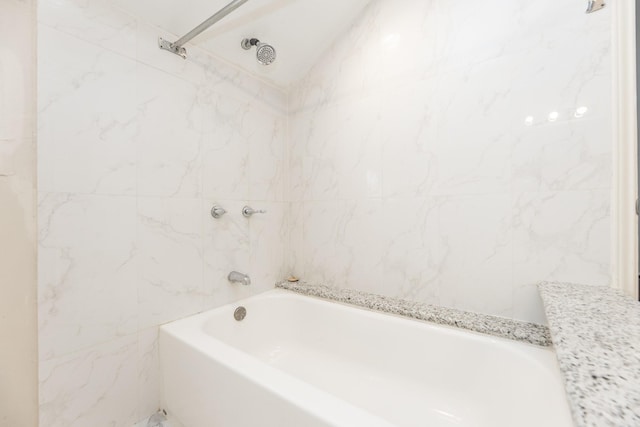 bathroom with bathing tub / shower combination and tile walls