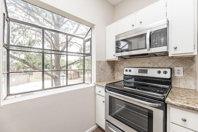 kitchen featuring stainless steel appliances, white cabinetry, and light stone counters