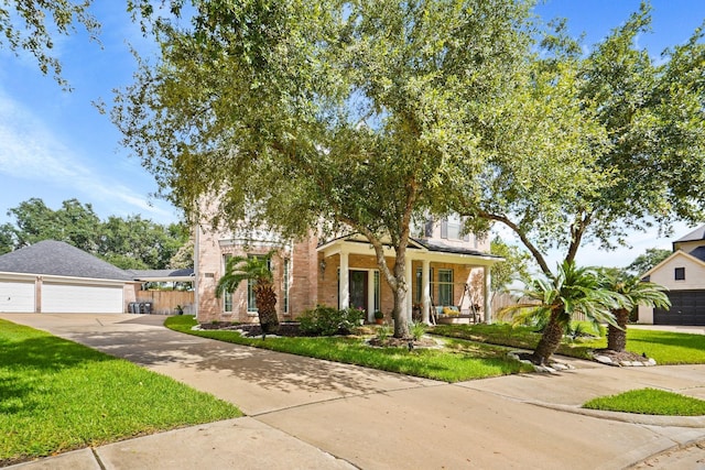 view of front of property featuring covered porch, a garage, and a front yard