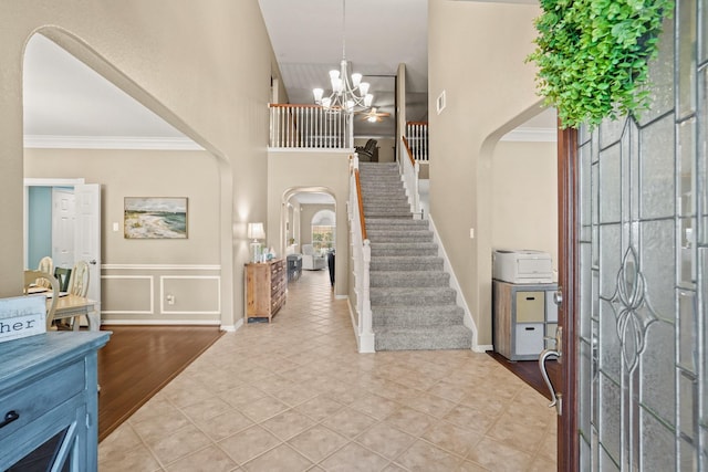 tiled foyer entrance with a chandelier and ornamental molding