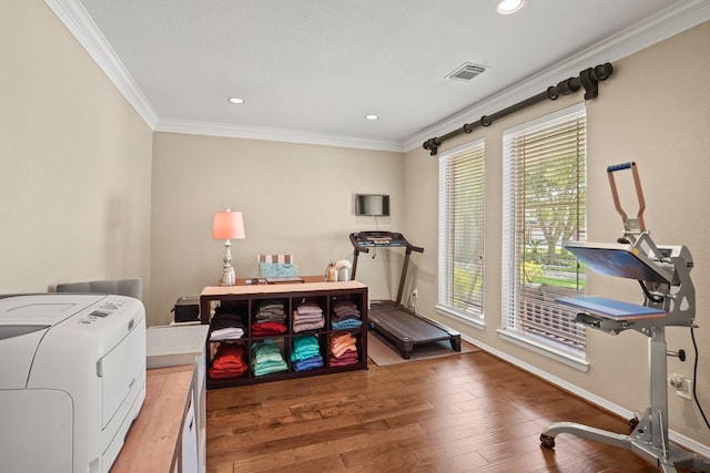 exercise area featuring hardwood / wood-style flooring, ornamental molding, and washer / clothes dryer