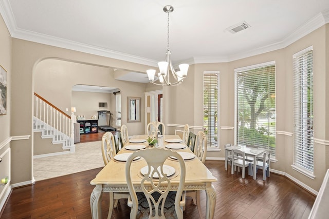 dining space with dark hardwood / wood-style floors, crown molding, and an inviting chandelier