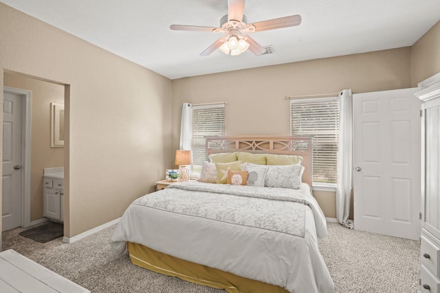 bedroom with ensuite bath, ceiling fan, light carpet, and multiple windows