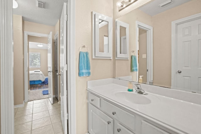 bathroom with tile patterned flooring, vanity, and a textured ceiling