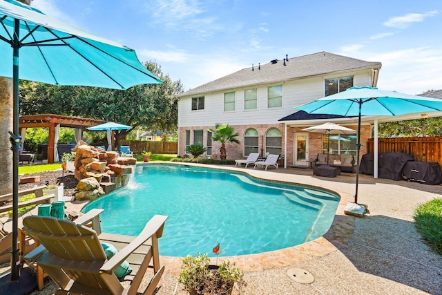 view of pool with pool water feature, a pergola, and a patio