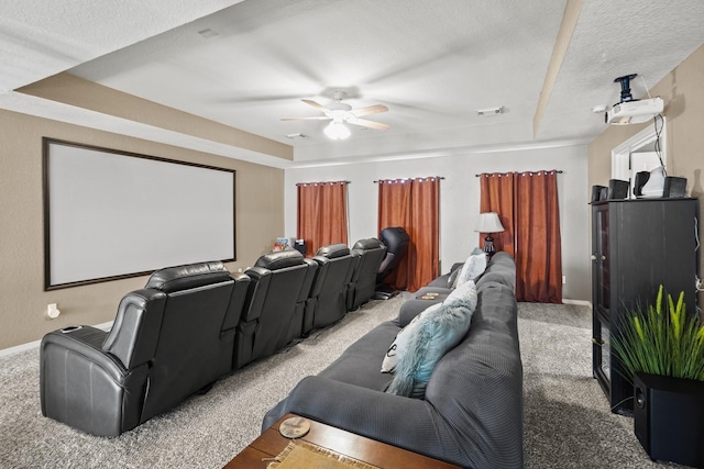 cinema featuring carpet flooring, a textured ceiling, a tray ceiling, and ceiling fan