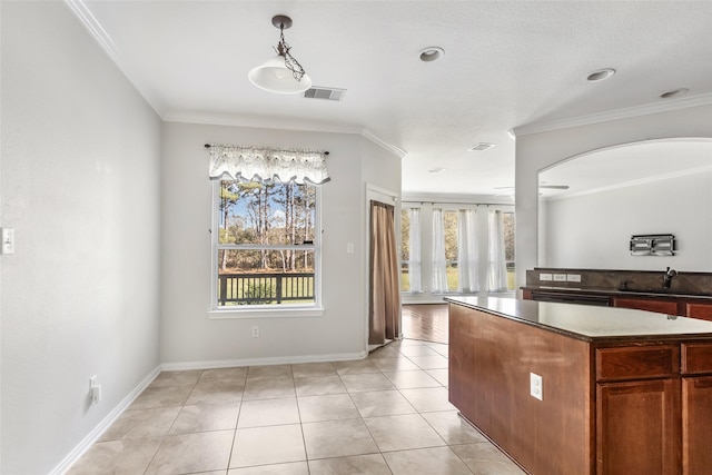 kitchen with crown molding, sink, light tile patterned floors, and plenty of natural light