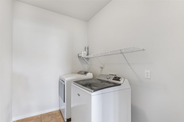 clothes washing area featuring light tile patterned floors and washer and dryer