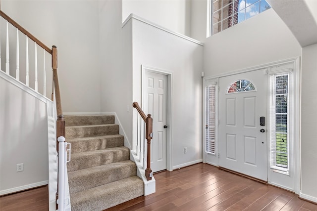 foyer entrance featuring hardwood / wood-style floors and a towering ceiling