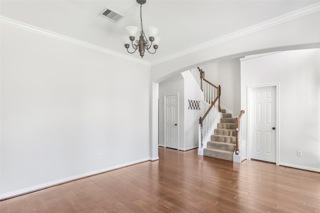 empty room with crown molding, wood-type flooring, and a notable chandelier