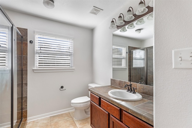 bathroom featuring tile patterned flooring, vanity, toilet, and walk in shower