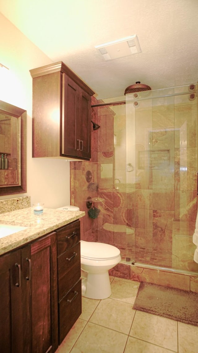 bathroom with an enclosed shower, vanity, toilet, and tile patterned floors