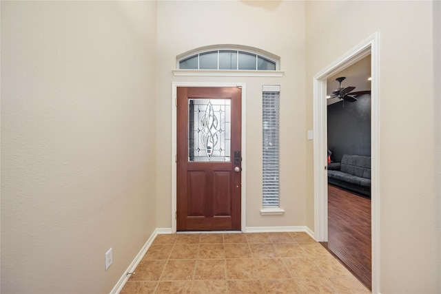 foyer featuring light tile patterned floors, ceiling fan, and a high ceiling