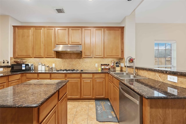 kitchen with dark stone counters, sink, light tile patterned floors, appliances with stainless steel finishes, and kitchen peninsula