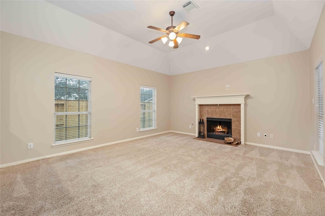 unfurnished living room with light carpet, vaulted ceiling, ceiling fan, a healthy amount of sunlight, and a tile fireplace