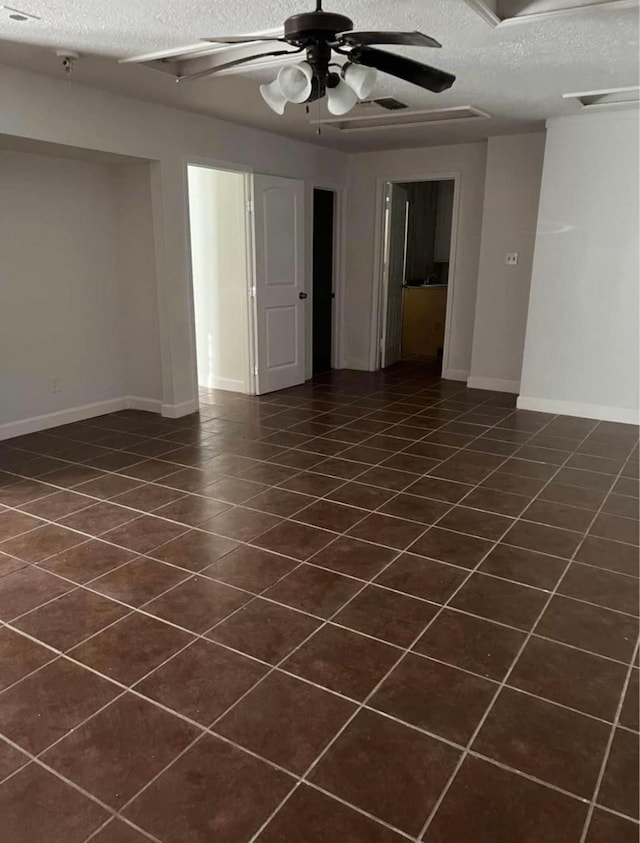 unfurnished room featuring ceiling fan, dark tile patterned flooring, and a textured ceiling