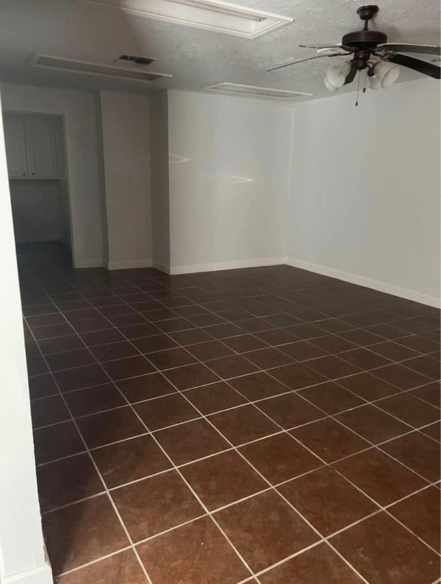 empty room with a textured ceiling, dark tile patterned flooring, and ceiling fan