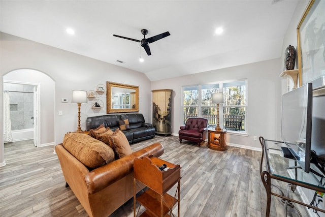 living room with ceiling fan, light hardwood / wood-style floors, and vaulted ceiling