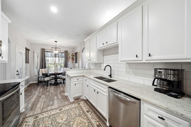 kitchen with white cabinetry, stove, stainless steel dishwasher, and decorative light fixtures