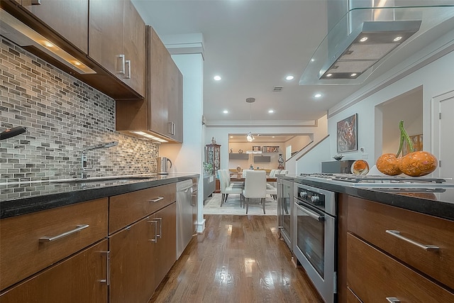 kitchen featuring light hardwood / wood-style floors, stainless steel appliances, backsplash, pendant lighting, and sink