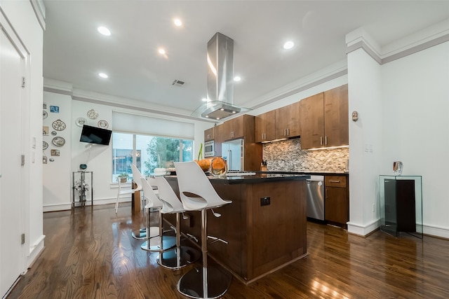 kitchen featuring island exhaust hood, appliances with stainless steel finishes, dark hardwood / wood-style floors, crown molding, and a center island