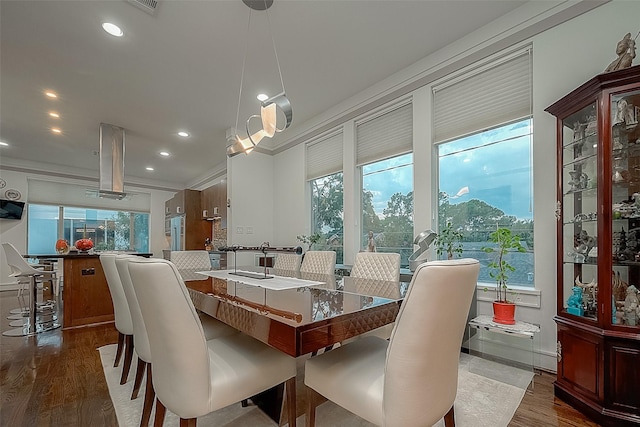 dining room featuring a healthy amount of sunlight, ornamental molding, and hardwood / wood-style floors