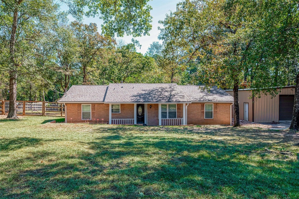 ranch-style home featuring covered porch, fence, a front lawn, and brick siding