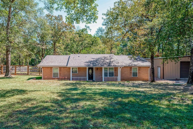 ranch-style home featuring covered porch, fence, a front lawn, and brick siding