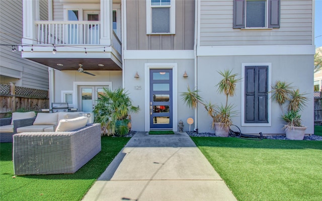 property entrance featuring an outdoor hangout area, a balcony, ceiling fan, a patio area, and a yard