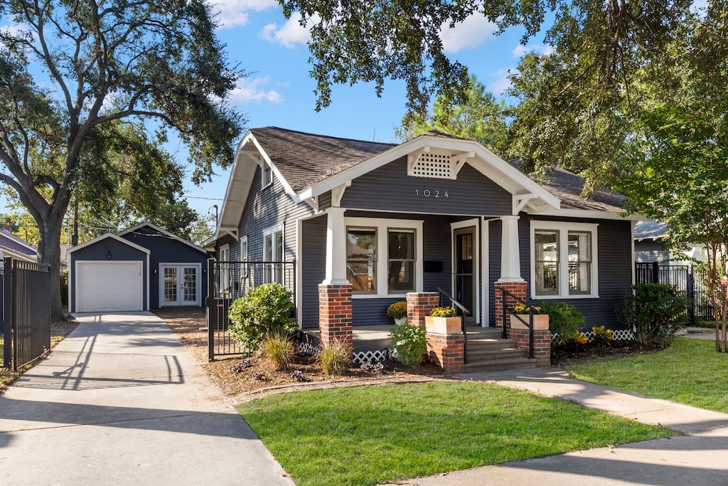 view of front of house with a front yard, a porch, a garage, and an outdoor structure