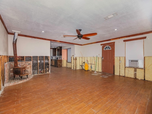 interior space featuring a wood stove, ceiling fan, hardwood / wood-style floors, and a textured ceiling