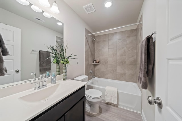 full bathroom with wood-type flooring, toilet, tiled shower / bath, and vanity