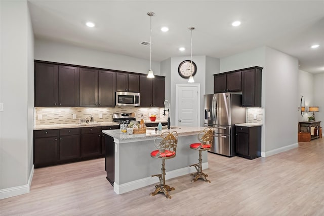 kitchen featuring dark brown cabinets, pendant lighting, sink, an island with sink, and stainless steel appliances