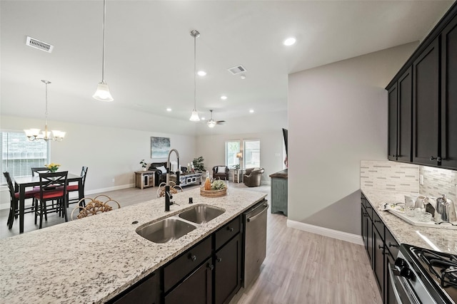 kitchen with appliances with stainless steel finishes, decorative light fixtures, backsplash, light stone countertops, and ceiling fan with notable chandelier