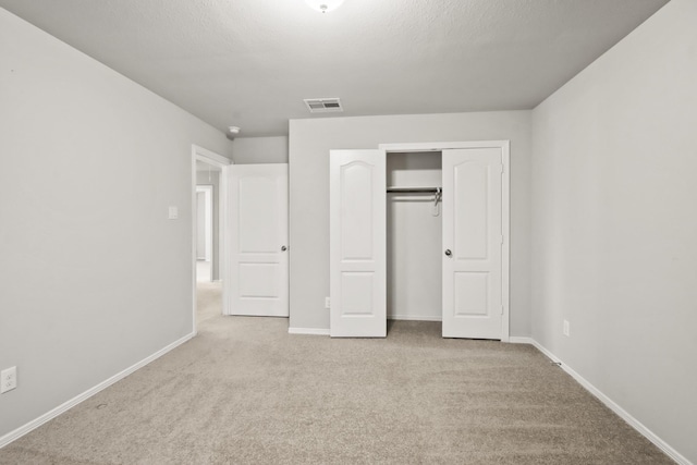 unfurnished bedroom with light carpet and a closet