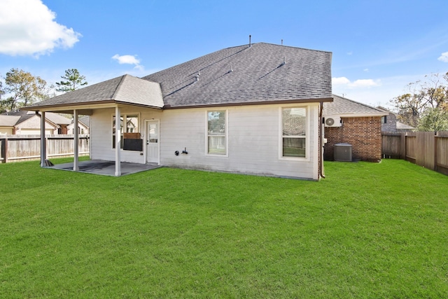 rear view of house with central AC, a patio area, and a lawn